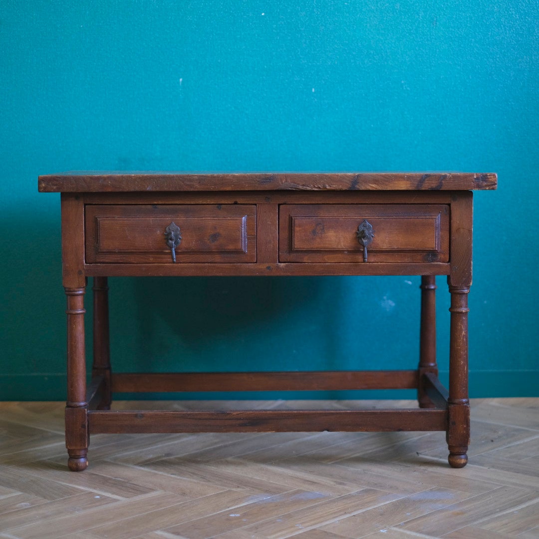 ーテーブルの正面からのアップ写真。オープン棚と、装飾的な前板を持つ2杯の引き出しが並んでいる